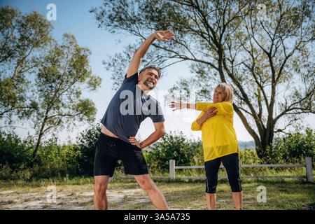 Heureux, faisant des exercices de fitness. Couple senior ensemble à l'extérieur à la nature. Banque D'Images