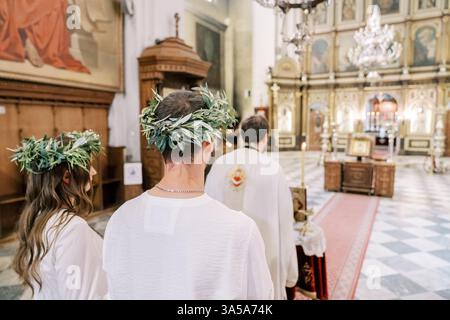 Monténégro, Kotor - 07 juillet 2024 : mariés et mariés en couronnes se tiennent derrière le prêtre menant la cérémonie de mariage. Vue arrière Banque D'Images