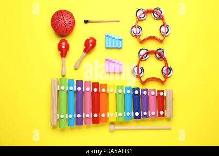 Composition de pose plate avec différents instruments de musique jouet sur fond jaune Banque D'Images