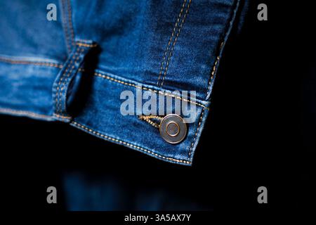 Un gros plan détaillé du bouton et des coutures sur un Jean bleu, soulignant son design et son savoir-faire. Idéal pour accentuer les détails Banque D'Images