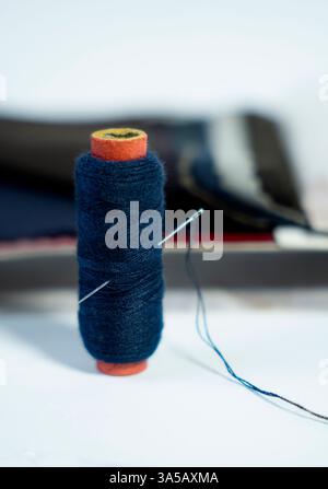 Bobine de fil et une aiguille, soigneusement disposés sur un fond blanc. Parfait pour créer des blogs, des tutoriels de couture et des projets créatifs. Banque D'Images