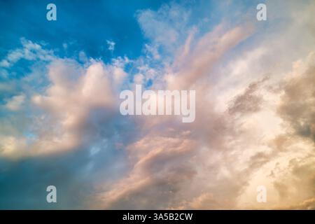 Capturez la beauté d'un ciel dynamique rempli de nuages doux et d'une palette bleue brillante au coucher du soleil. La scène évoque sérénité et émerveillement. Banque D'Images