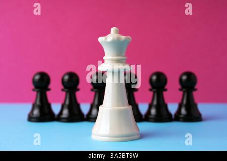 Échecs de reine blanche devant le pion noir sur fond rose Banque D'Images