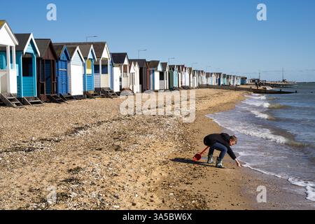 Un homme attrapant du poisson près de la ligne de flottaison sur la plage avec rangée de cabanes de plage sur un jour ensoleillé de printemps, Southend-on-Sea plage Essex Angleterre Royaume-Uni Banque D'Images