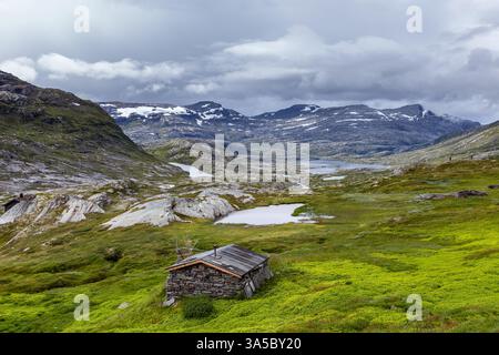 Paysage scandinave à couper le souffle avec terrain montagneux, verdure luxuriante, et une cabane pittoresque nichée dans la nature sauvage reculée sous un spectaculaire Banque D'Images