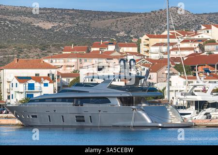Moderne, élégant, gris yacht de luxe est amarré dans le port de Rogoznica, Croatie, entouré par les charmantes maisons au toit rouge de la ville et le bleu Banque D'Images