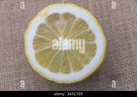 Photographie rapprochée d'un demi-citron sur un fond de toile de jute, vue de dessus. Banque D'Images