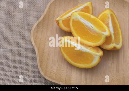 Oranges tranchées sur une plaque en bois, avec une vue de haut en bas, gros plan, fond de toile de jute. Banque D'Images
