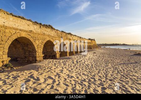 L'aqueduc, construit au début de la période byzantine. Coucher de soleil fantastique sur la côte méditerranéenne à Césarée. La plage de sable est piétinée par les touristes. C Banque D'Images