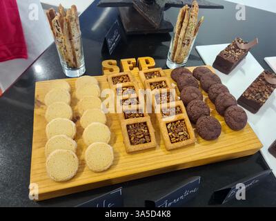 Une sélection magnifiquement agencée de produits de boulangerie présente un assortiment de biscuits et de desserts, attirant les visiteurs dans une boulangerie accueillante. Banque D'Images