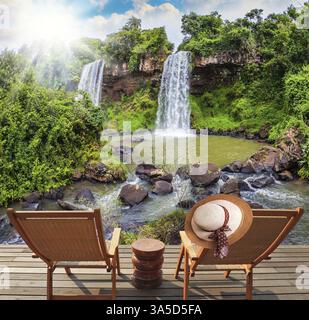 Deux cascades de Iguazu Falls tombent dans un petit étang tranquille. Le concept de tourisme écologique. Deux chaises longues en bois se tiennent près des cascades. Banque D'Images