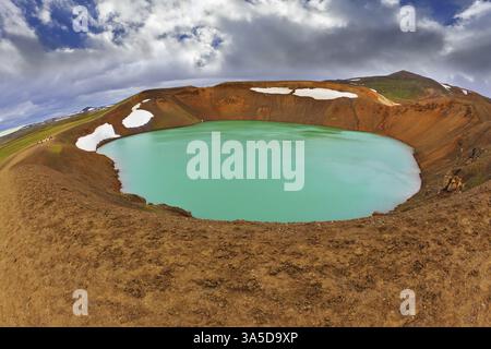 Lac Krafla dans le cratère d'un volcan éteint. Couleur vert vif de l'eau du lac. Sur les rives se trouvent des champs de neige de l'année dernière Banque D'Images