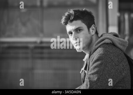 Beau jeune homme dans la ville, éclairées par la lumière au coucher du soleil, dans un noir et blanc tourné Banque D'Images