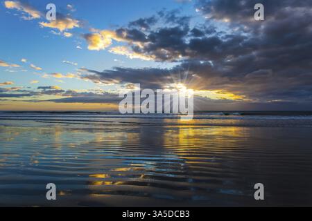Lever du soleil sur l'océan. Les couleurs douces des nuages se reflètent dans l'océan. Les rayons du soleil traversent les nuages légers du matin. posta artistique Banque D'Images