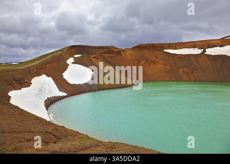 Pittoresque lac Krafla dans le cratère d'un volcan éteint. Couleur vert vif de l'eau du lac. Sur les rives se trouvent des champs de neige de l'année dernière Banque D'Images