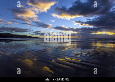 Les couleurs douces des nuages se reflètent dans l'eau de l'océan. Matin calme. Un vent léger provoque de petites ondulations dans l'eau. Nouvelle-Zélande, Côte Pacifique. Le conc Banque D'Images