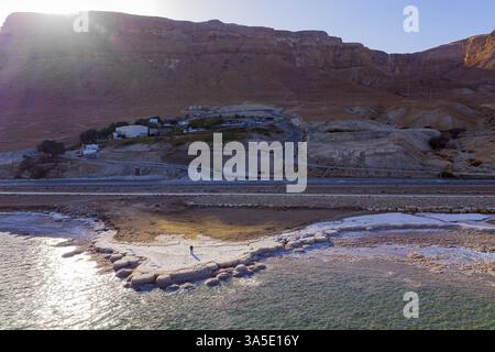 Shallow Dead Sea photographiée depuis un drone. Du sel évaporé a été déposé le long du rivage. Une autoroute asphaltée longe le littoral. L'hiver à de Banque D'Images
