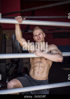 Beau jeune homme musclé debout contre des barres horizontales, regardant la caméra Banque D'Images