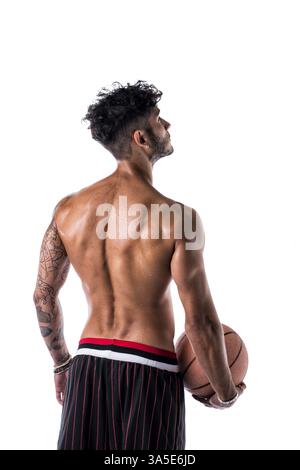 Jeune homme athlétique isolé sur fond blanc holding basketball ball, vue latérale arrière Banque D'Images