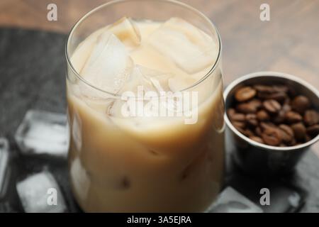 Liqueur de crème de café en verre, glaçons et haricots sur la table, gros plan Banque D'Images