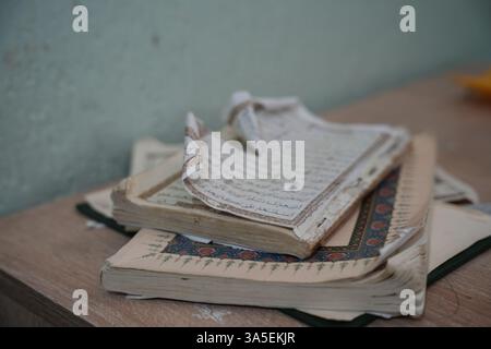 Misrata, Libye. 23 mars 2025. Le Saint Coran repose ouvert à l'intérieur de l'une des plus anciennes mosquées d'Afrique du Nord en Libye. Ses pages usées continuent de guider des générations à travers des siècles de foi et d'apprentissage. Les enfants libyens sont assis dans une école coranique traditionnelle, inscrivant soigneusement des versets sur des tablettes de bois pendant que leur professeur les guide dans la récitation. Cette méthode séculaire, ravivée pendant le Ramadan, reste une pratique chère pour mémoriser le Saint Coran. Crédit : SOPA images Limited/Alamy Live News Banque D'Images