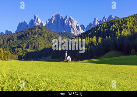 Italie, Tyrol. Petite église blanche avec une cloche parmi les pelouses vertes au coucher du soleil. Le plus beau village du monde, Santa Maddalena dans le Val di F. Banque D'Images