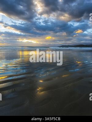 Lever du soleil sur l'océan. Les couleurs douces des nuages se reflètent dans l'eau de l'océan. Un vent léger provoque de petites ondulations dans l'eau. L'art du photog artistique Banque D'Images