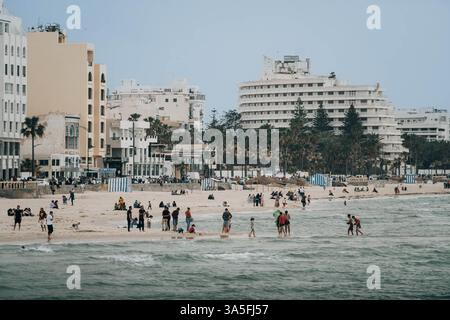 Une vue panoramique sur la plage de Bou Jaafar, Sousse, Tunisie, avec des rivages de sable doré, des eaux turquoises, des palmiers balançant et une vie côtière animée. Banque D'Images