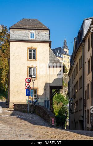 Une vieille maison de ville dans une rue pavée dans le quartier Grund à Luxembourg ville, avec le clocher de l'église Saint-Michel au loin Banque D'Images