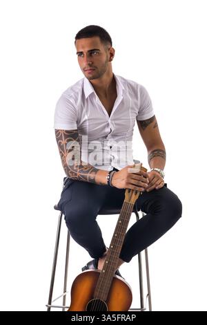 Beau jeune homme en noeud papillon avec guitare regardant la caméra. Studio shot isolé sur fond blanc Banque D'Images