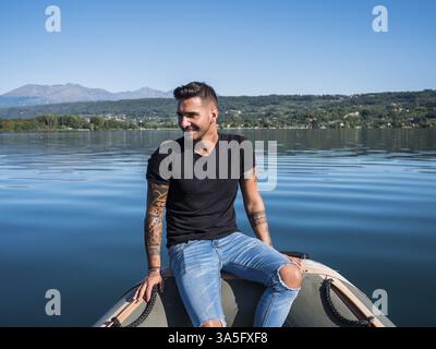 Portrait d'un jeune bel homme au corps tatoué regardant la caméra naviguant en bateau Banque D'Images