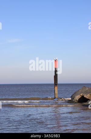 Un poteau de marquage à l'extrémité d'un groyne de roches importées sur la côte nord-est du Norfolk à Waxham, Norfolk, Angleterre, Royaume-Uni. Banque D'Images
