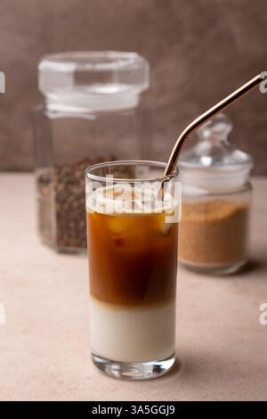 Café avec lait de coco et glaçons dans un grand verre. Boisson froide traditionnelle sans alcool. En arrière-plan, un pot de café et un pot de sucre. S Banque D'Images