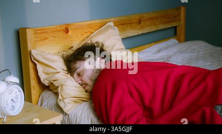Homme dormant paisiblement dans son lit – sommeil profond ou repos fatigué Banque D'Images
