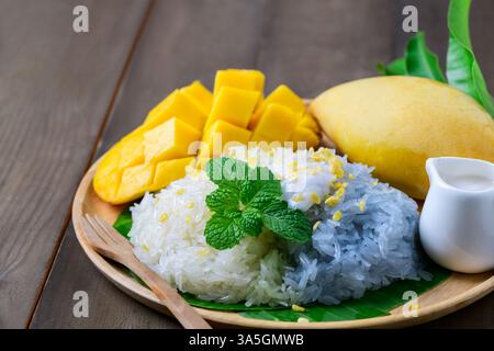 Riz collant à la mangue mûre avec du lait de noix de coco sur fond de bois. Dessert thaïlandais traditionnel Banque D'Images