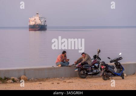 Deux Libanais locaux sur le front de mer de Beyrouth, avec la moto, et le cargo sur la mer Méditerranée. Banque D'Images