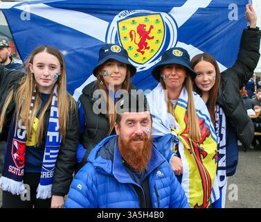 23 mars 2025. Glasgow, Royaume-Uni. Les supporters écossais et grecs arrivent à Hampden Park, Glasgow, en Écosse, pour participer au match de l'UEFA Nations League entre l'Écosse et la Grèce. Fan de football écossais, posant avec sa femme et ses trois filles tout en tenant un drapeau écossais de football. Crédit : Findlay / Alamy Live News Banque D'Images
