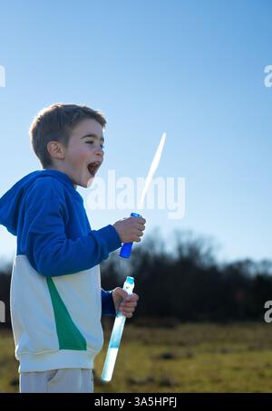 Enfant heureux soufflant des bulles de savon dans un champ par une journée ensoleillée brillante Banque D'Images