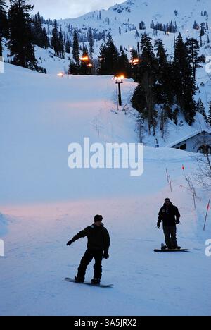 Deux snowboarders se dirigent vers le bas de la colline lors de la dernière course de la journée Banque D'Images