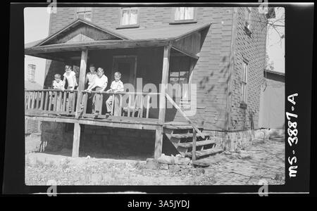 Cette photographie de 1946 montre la famille d’un mineur sur le porche avant de la maison appartenant à leur société à la mine Victor #17 de Cherrytree Coal Company à Emeigh Run, en Pennsylvanie. La maison était en mauvais état. Banque D'Images
