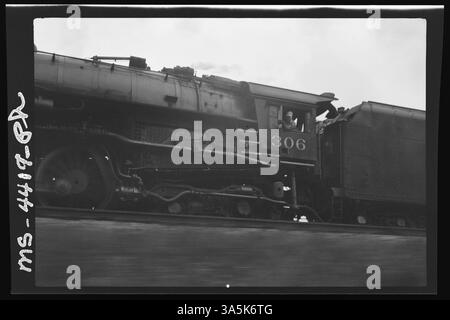 Cette image de 1946 capture un train en mouvement avec le conducteur visible regardant par la fenêtre, offrant un aperçu du transport ferroviaire du milieu du XXe siècle. La photographie illustre les opérations quotidiennes du système ferroviaire à cette époque. Banque D'Images