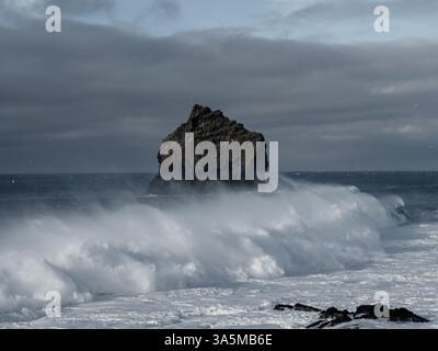 Une pile de mer solitaire s'élève contre les vagues écrasantes de l'Atlantique à Valahnúkamöl, créant un paysage marin spectaculaire de roches volcaniques escarpées, de marées puissantes, et un Banque D'Images