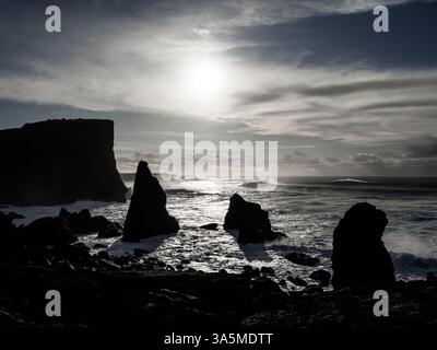 Coucher de soleil spectaculaire sur Valahnúkamöl, Islande. Des piles de mer déchiquetées s'élèvent de l'Atlantique turbulent tandis que le soleil projette de longues ombres, éclairant la puissance A. Banque D'Images