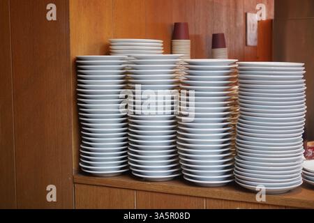 Des assiettes blanches empilées soigneusement disposées dans un coin cuisine du restaurant Banque D'Images