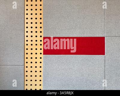 Série de panneaux muraux rembourrés gris avec tissu rouge et plaque métallique or perforée. Cela fonctionne comme un coussin rembourré mur à l'isolation phonique, ou un Banque D'Images