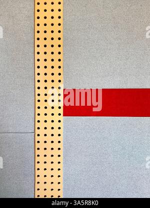 Série de panneaux muraux rembourrés gris avec tissu rouge et plaque métallique or perforée. Cela fonctionne comme un coussin rembourré mur à l'isolation phonique, ou un Banque D'Images