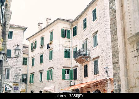 Monténégro, Kotor - 07 juillet 2024 : anciennes maisons en pierre avec volets verts sur les fenêtres des rues étroites. Kotor, Monténégro Banque D'Images