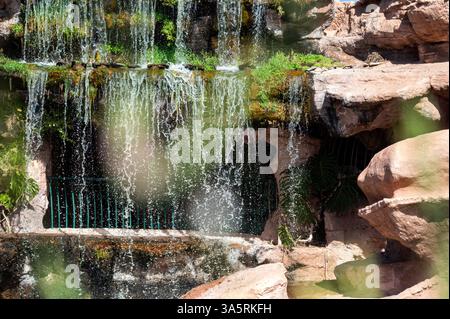 L'eau coule le long d'une surface rocheuse entourée de verdure luxuriante dans le paysage pittoresque du Maroc. Banque D'Images