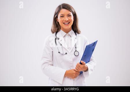Studio a photographié le portrait d'un médecin féminin joyeux qui tient un presse-papiers et sourit. Banque D'Images