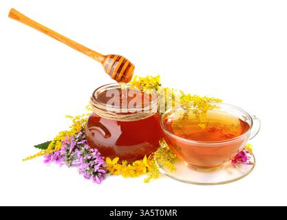 Miel et thé dans une tasse en verre avec des fleurs et une cuillère en bois isolé sur fond blanc Banque D'Images